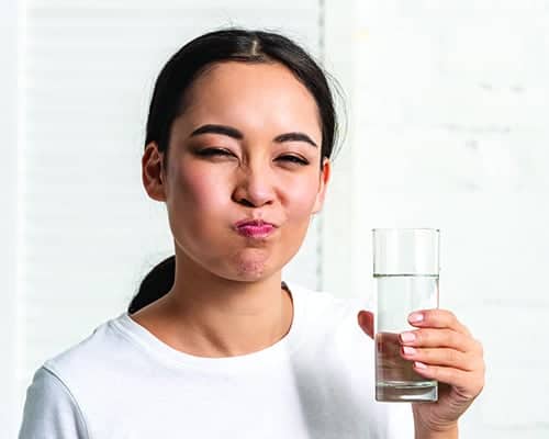 Woman holding a glass of water with a neutral background