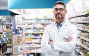friendly male pharmacist standing in pharmacy